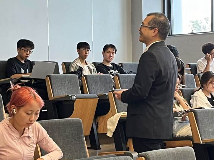 A person standing in front of a group of people in a lecture hallDescription automatically generated